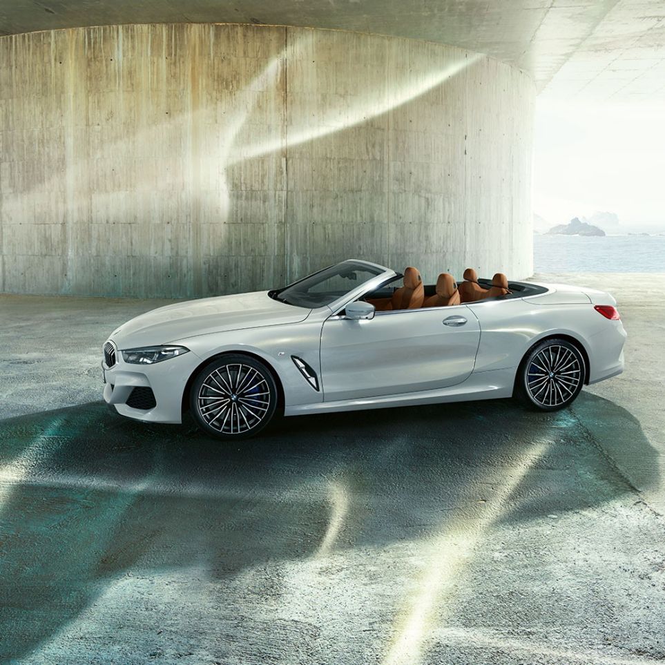 Imagine din lateral cu BMW M850i xDrive în Alb Mineral metalizat şi cu soft-top-ul deschis. Imagine din lateral cu BMW M850i xDrive în Alb Mineral metalizat şi cu soft-top-ul deschis.