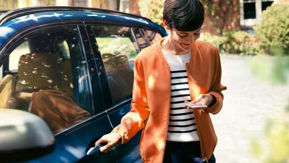 BMW Teleservices BMW Teleservices, femeie cu smartphone lângă portiera BMW