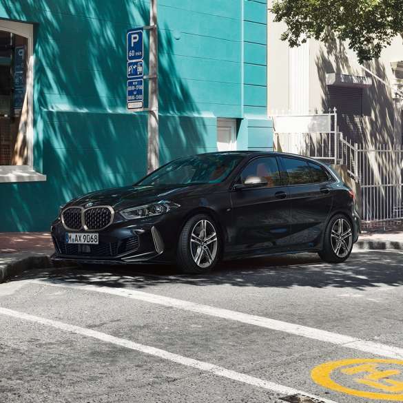 Imagine cu trei sferturi din partea laterală a BMW M135i xDrive. Imagine cu trei sferturi din partea laterală a noului BMW M135i xDrive în Negru Sapphire metalizat, parcând.