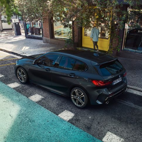 BMW M135i xDrive, parcând. Perspectivă de sus asupra părţii laterale a BMW M135i xDrive în Negru Sapphire metalizat, parcând.
