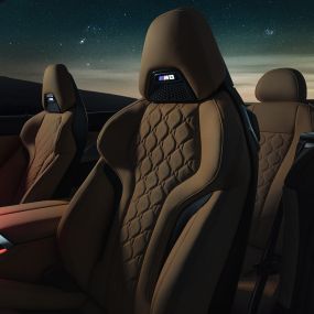 Scaune M Sport din piele Merino. Interiorul BMW M8 Cabriolet cu soft-top-ul deschis, cu scaune M Sport din piele Merino şi iuminare ambientală roşie, sub cerul înstelat.
