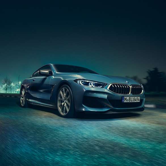 Imagine cu trei sferturi din partea drepată faţă a BMW M850i xDrive Coupé. Imagine cu trei sferturi din partea drepată faţă a BMW M850i xDrive Coupé în Albastru Barcelona metalizat, rulând pe timp de noapte.
