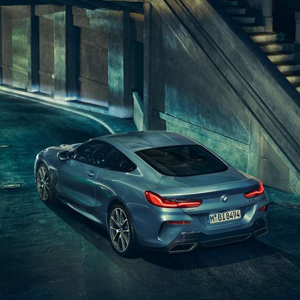 Imagine cu trei sferturi din partea spate stânga a BMW M850i xDrive Coupé. Imagine cu trei sferturi din partea spate stânga a BMW M850i xDrive Coupé în Albastru Barcelona metalizat, staţionând pe timp de noapte.