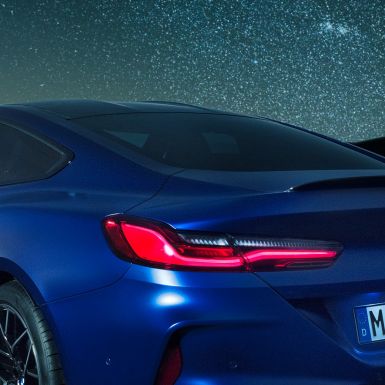Spoiler M pentru partea spate Imagine în prim-plan cu secţiunea umărului BMW M8 Competition Coupé în Albastru Marina Bay metalizat, cu spoiler M pentru partea spate din carbon, pe timp de noapte.