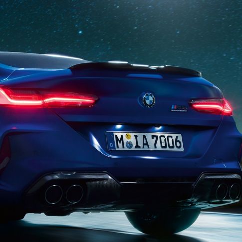 Difuzor M în Negru Carbon. Imagine în prim-plan cu partea spate a BMW M8 Competition Coupé în Albastru Marina Bay metalizat, cu difuzor M în Negru Carbon, pe timp de noapte.