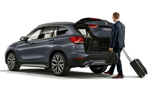 BMW X1 cu sistem de deschidere şi închidere fără atingere a hayonului. Imagine din lateral cu BMW X1 staţionând cu hayonul deschis.