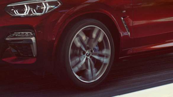 Suspensia M adaptivă a BMW X4 Imagine cu trei sferturi din partea laterală şi cu jantele din aliaj uşor ale BMW X4 M40i, G02, 2018, în Roşu Flamenco Brilliant Effect, cu suspensie M adaptivă