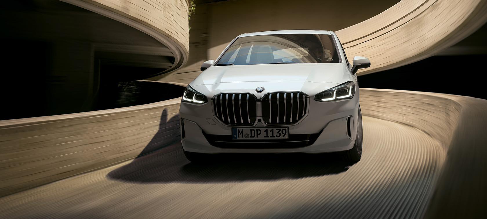 Imagine din partea frontală a BMW Seria 2 Active Tourer, în Alb Mineral, în timp ce se deplasează într-o parcare