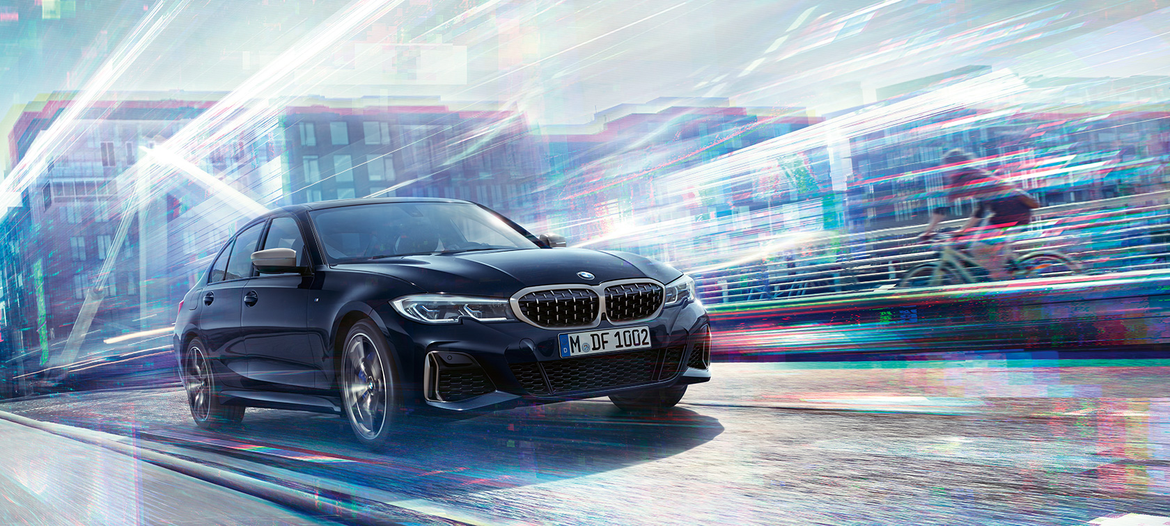 BMW M340i xDrive al BMW Seria 3 Sedan. Imagine cu trei sferturi din partea laterală a BMW M340i xDrive rulând pe drum, pe un fundal urban.