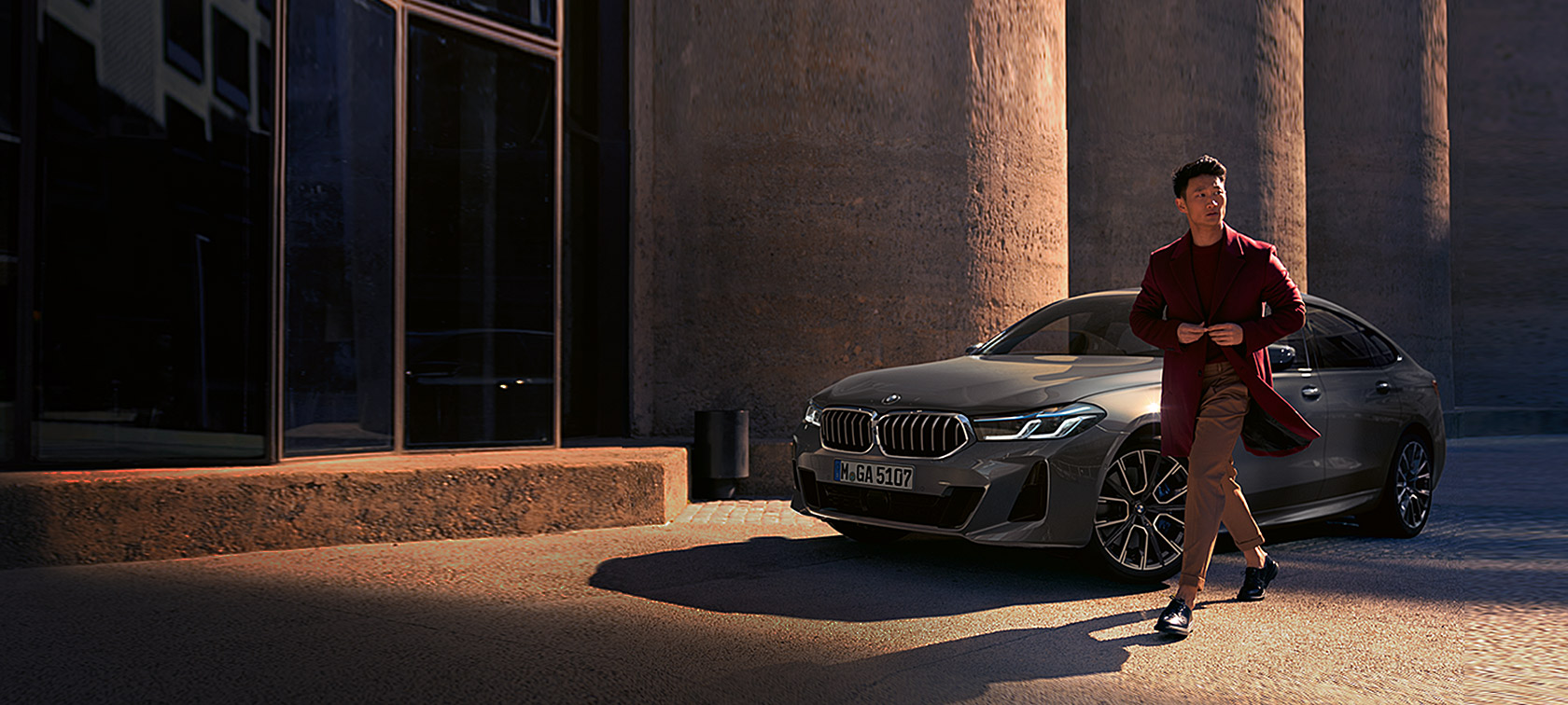 Imagine cu trei sferturi din partea frontală a BMW Seria 6 Gran Turismo 640i xDrive, G32, 2020, în Gri Bernina, cu un bărbat în faţă