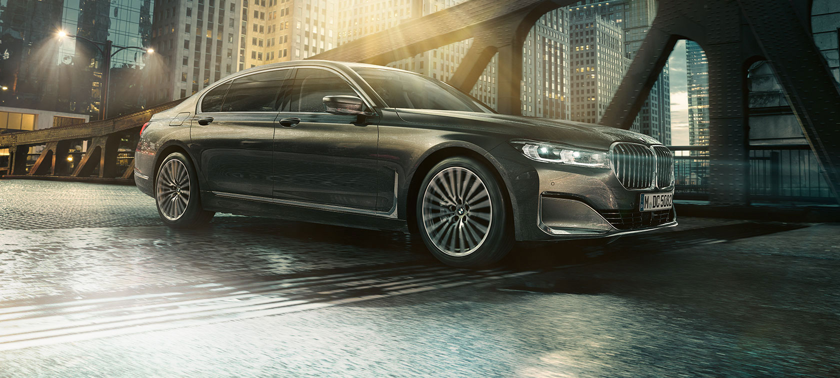 Perspectivă laterală asupra BMW Seria 7 Sedan Perspectivă laterală asupra BMW Seria 7 Sedan cu o portieră deschisă, în faţa unui hotel iluminat