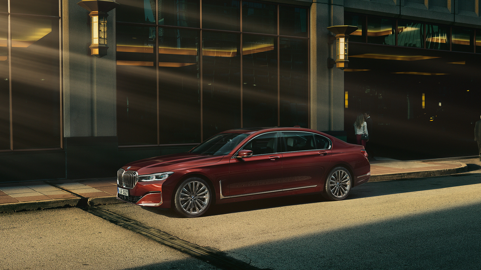 Imagine din lateral cu BMW Individual Seria 7 Sedan Imagine din lateral cu BMW Individual Seria 7 Sedan roşu în faţa unui peisaj urban