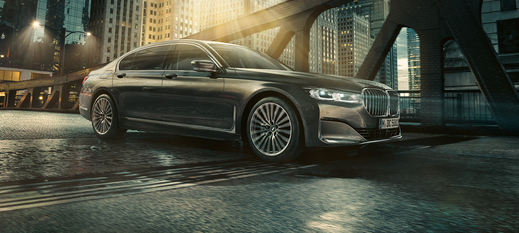 Imagine din partea laterală a unui BMW Seria 7 Sedan Imagine din partea laterală a unui BMW Seria 7 Sedan cu uşa deschisă, în faţa unui hotel iluminat