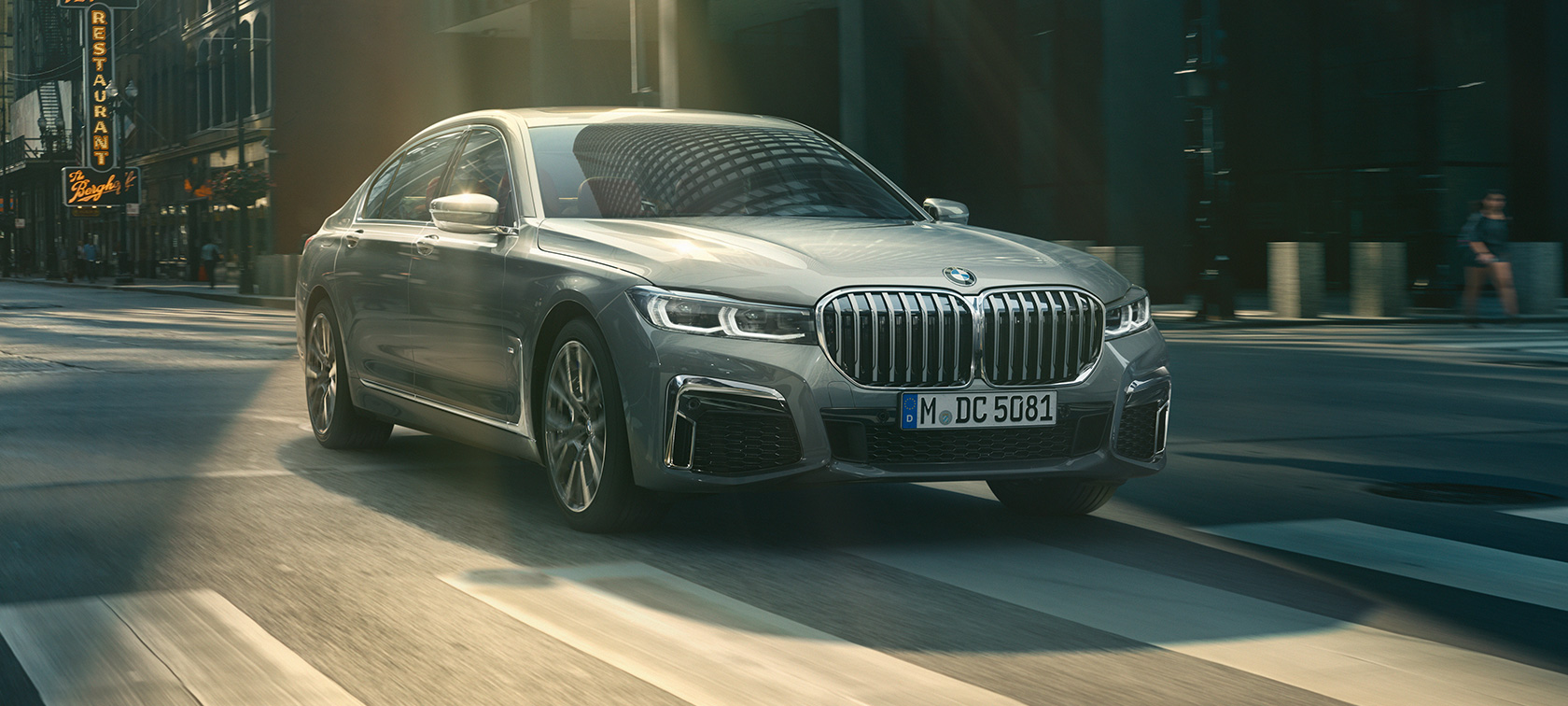 Imagine cu trei sferturi din partea frontală a unui BMW Seria 7 Sedan gri care se deplasează Imagine cu trei sferturi din partea frontală a unui BMW Seria 7 Sedan gri care se deplasează într-o zonă urbană