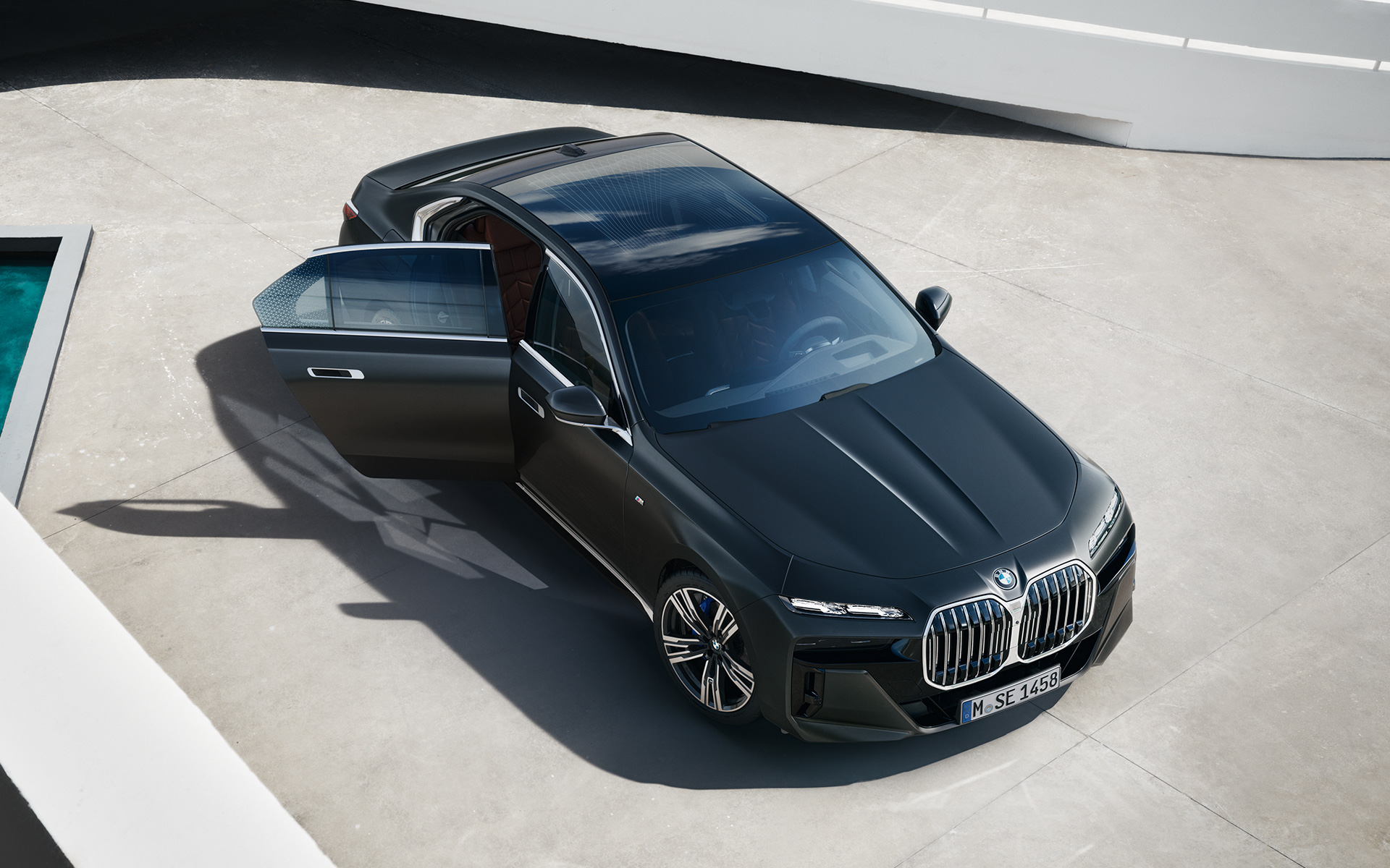 Imagine de sus cu un BMW Seria 7 Sedan G70 ICE 740i, Gri Frozen Deep, cu pachet M Sport BMW Seria 7 Sedan G70 ICE 740i, Gri Frozen Deep, cu pachet M Sport, imagine de sus cu portiera pasagerului din dreapta deschisă