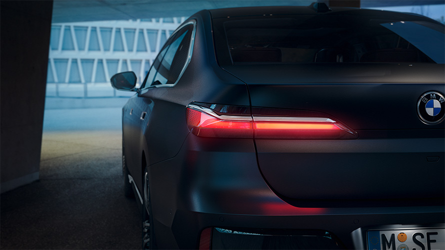 BMW Seria 7 Sedan G70 ICE 740i, Gri Frozen Deep, cu pachet M Sport, imagine din partea din spate cu stopuri aprinse într-un tunel