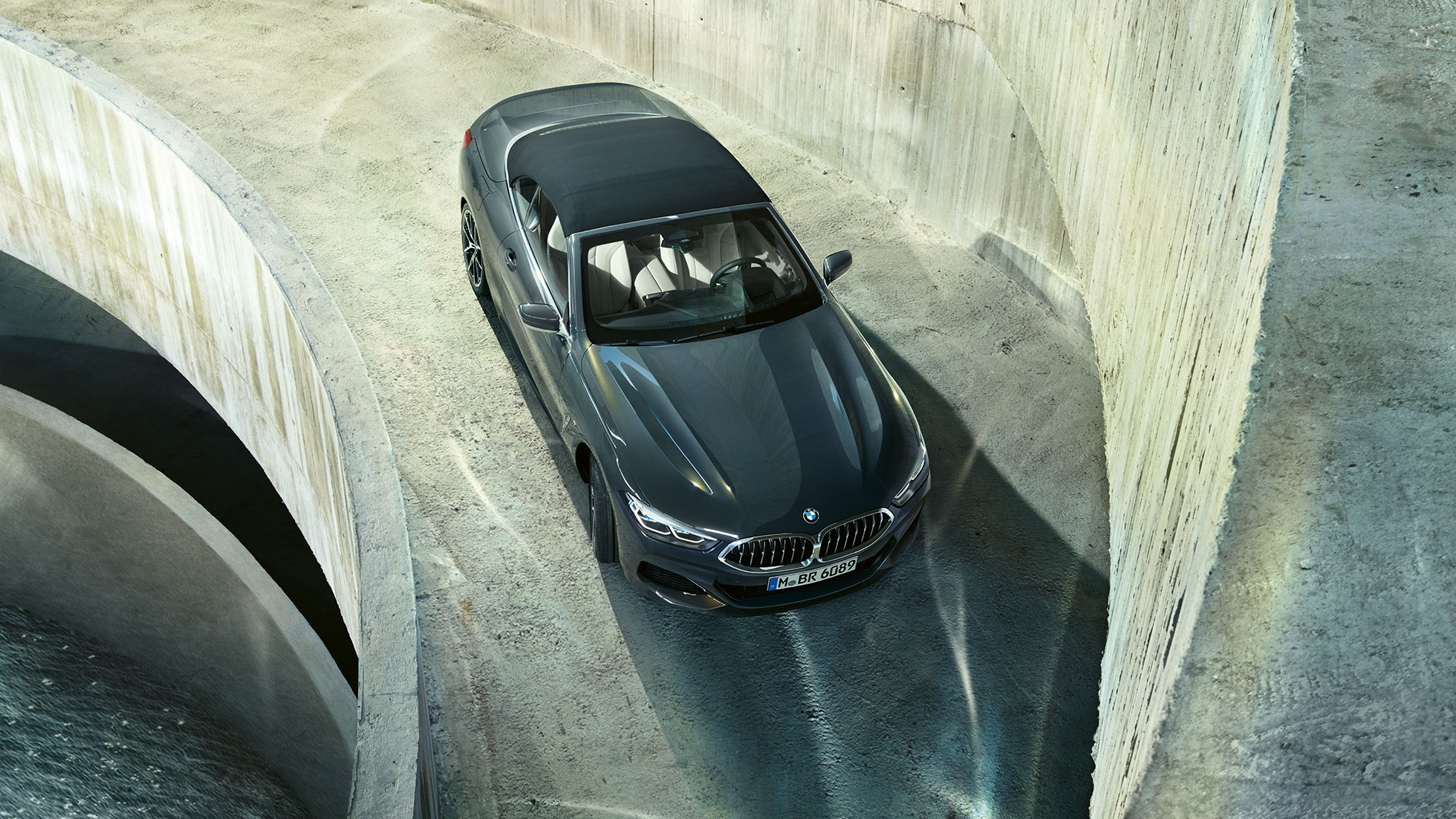 Perspectivă de sus asupra BMW M850i xDrive în Gri Dravit metalizat cu soft-top negru. Perspectivă de sus asupra BMW M850i xDrive în Gri Dravit metalizat cu soft-top negru.