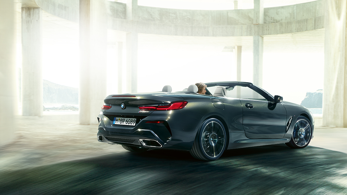 Imagine laterală a BMW M850i xDrive rulând cu soft-top-ul deschis. Imagine laterală a BMW M850i xDrive rulând cu soft-top-ul deschis.