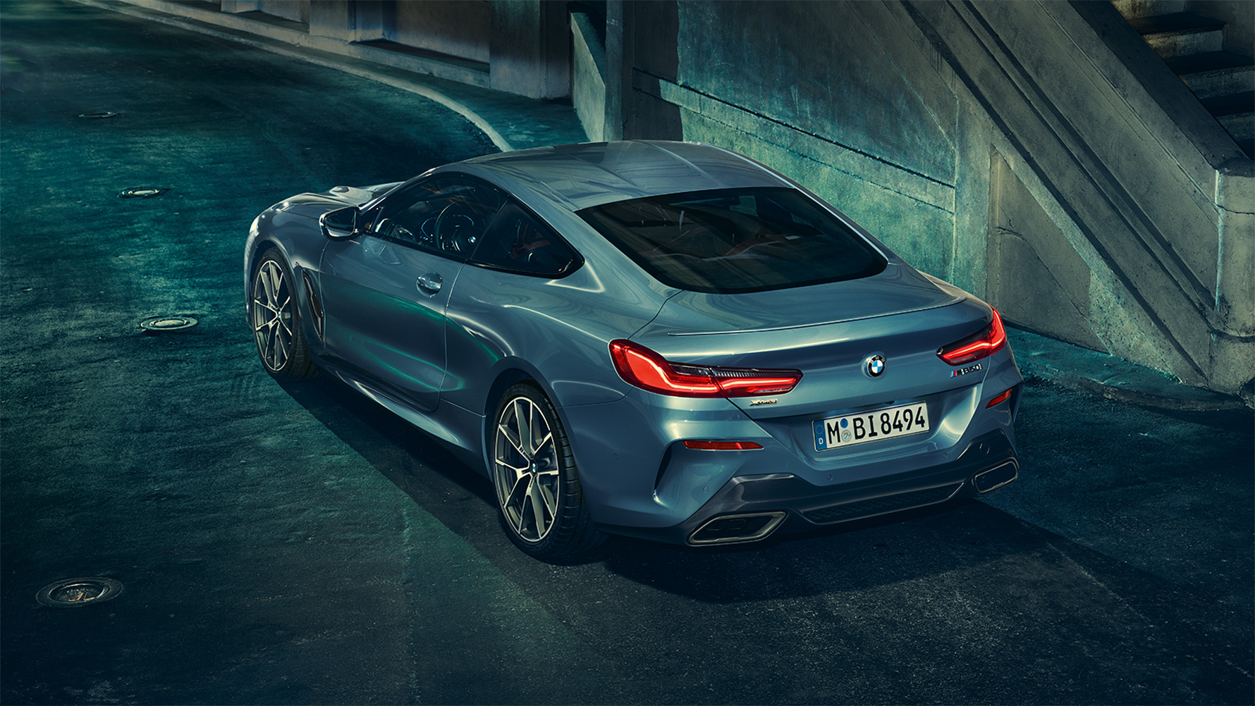 Imagine cu trei sferturi din partea spate a BMW Seria 8 Coupé Imagine cu trei sferturi din partea spate a BMW Seria 8 Coupé pe timp de noapte, în faţa unui peisaj urban.