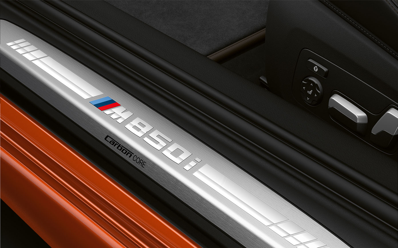 Pragurile portierelor BMW Seria 8 Coupé cu logo „M850i”. Imagine în prim-plan cu pragurile portierelor BMW Seria 8 Coupé cu logoul „M850i”.
