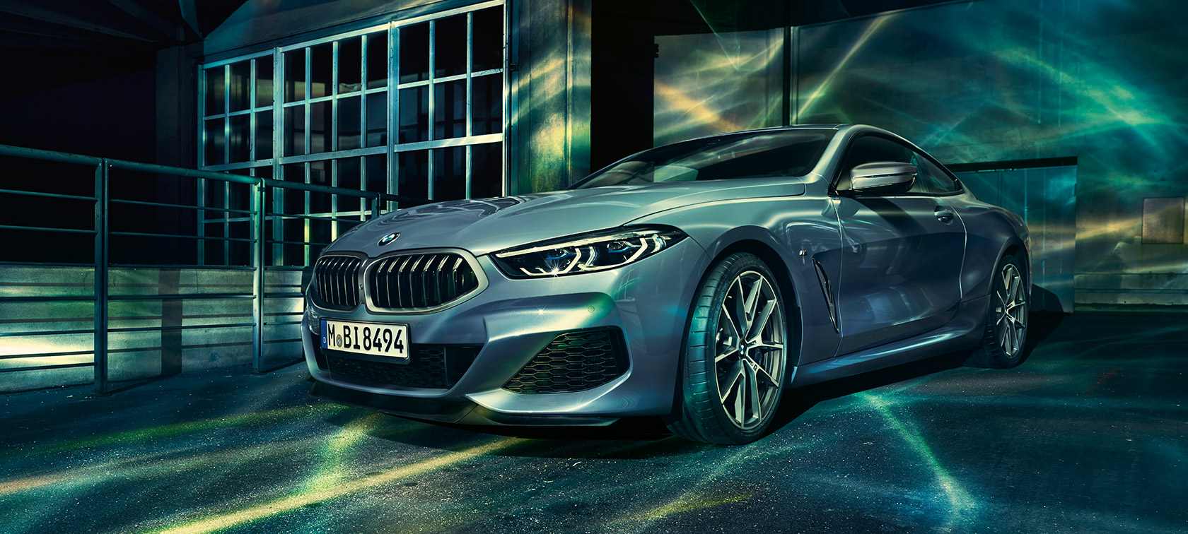 Imagine cu trei sferturi din partea frontală a BMW Seria 8 Coupé. Imagine cu trei sferturi din partea frontală a BMW Seria 8 Coupé în faţa unei clădiri industriale.