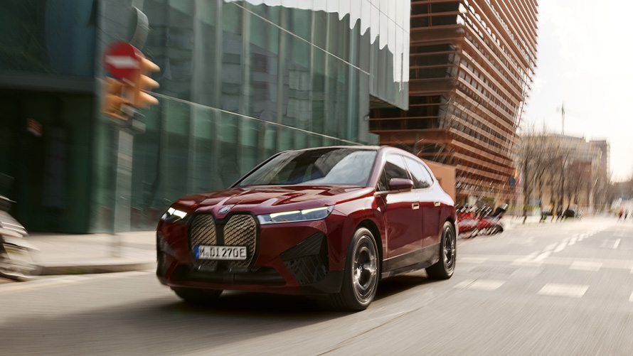 BMW iX i20 SUV electric BMW iX xDrive50 asistenţă la condus BMW iX i20 2021 SUV electric BMW iX xDrive50 în Roşu Aventurin în timp ce conduce într-un mediu urban