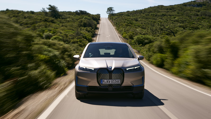 Imagine din partea frontală a BMW iX, pe şosea Imagine din partea frontală a BMW iX i20, Argintiu Cashmere, pe şosea