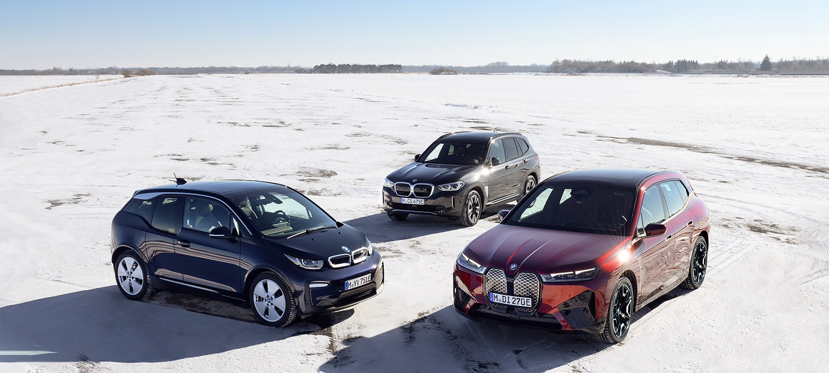 Imagine cu trei sferturi din partea laterală a unor automobile electrice BMW staţionând pe nisip, văzute de sus Imagine cu trei sferturi din partea laterală a unor automobile electrice BMW - BMW Seria i - staţionând pe nisip, văzute de sus