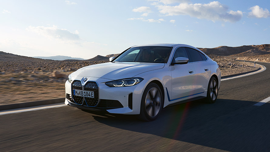 Imagine cu trei sferturi din partea frontală a unui BMW i4 G26 din prima generaţie în timp ce se deplasează Imagine cu trei sferturi din partea frontală a unui BMW Seria i BMW i4 G26 din prima generaţie în timp ce se deplasează