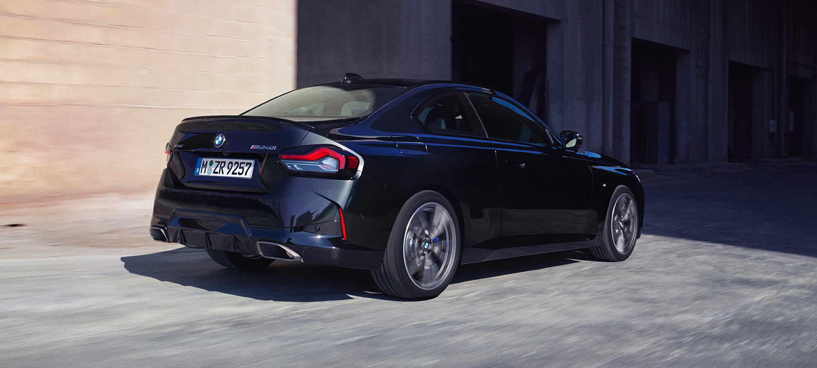 Imagine cu trei sferturi din partea din spate a BMW M240i xDrive Coupé G42 2021 Imagine cu trei sferturi din partea din spate a BMW M240i xDrive Coupé G42 2021 în Negru Sapphire, rulând