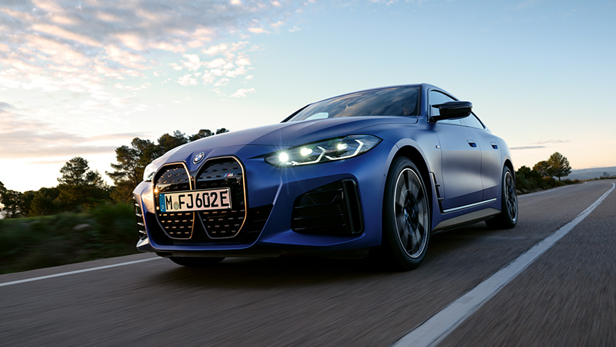 Imagine cu trei sferturi din partea frontală, în contraplonjeu, a unui BMW i4 M50 G26 2021 Imagine cu trei sferturi din partea frontală, în contraplonjeu, a unui BMW i4 M50 G26 2021 BMW Individual Albastru Frozen Portimao în timp ce se deplasează