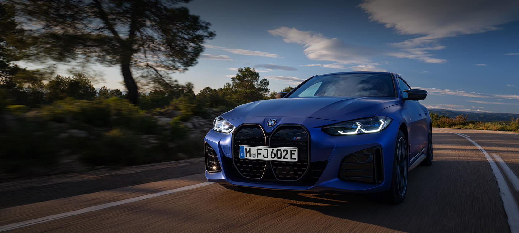 Imagine cu trei sferturi din partea frontală a unui BMW i4 M50 G26 2021 BMW Individual Albastru Frozen Portimao &icirc;n timp ce se deplasează