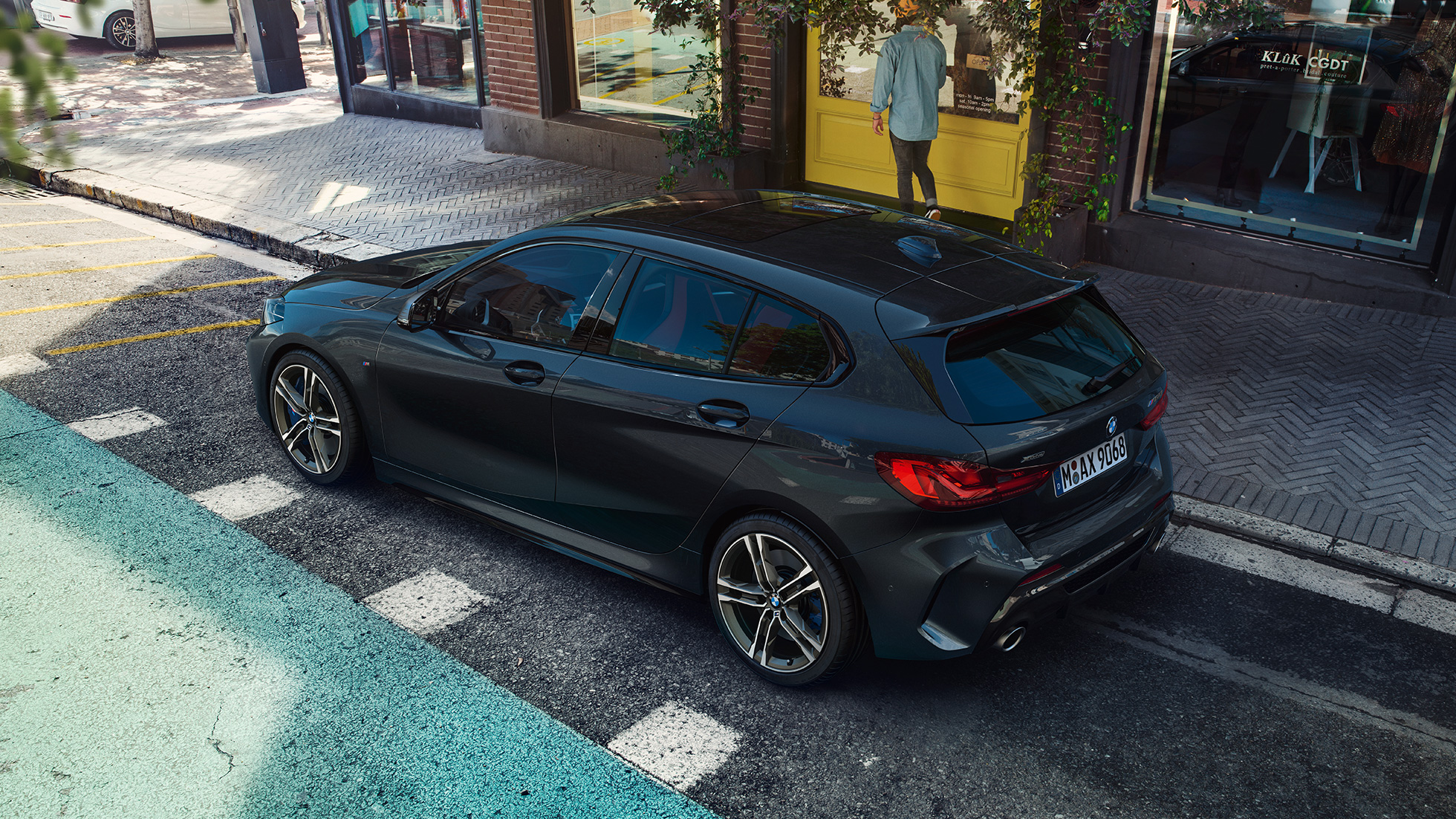 BMW M135i xDrive, parcând. Perspectivă de sus asupra părţii laterale a BMW M135i xDrive în Negru Sapphire metalizat, parcând.