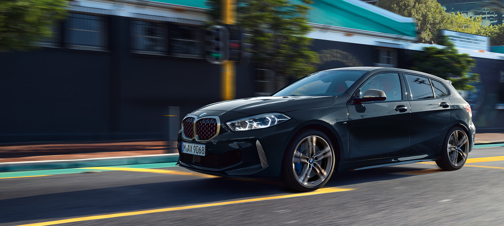 Noul BMW M135i xDrive Imagine cu trei sferturi din partea laterală a noului BMW M135i xDrive în Negru Sapphire metalizat, rulând.