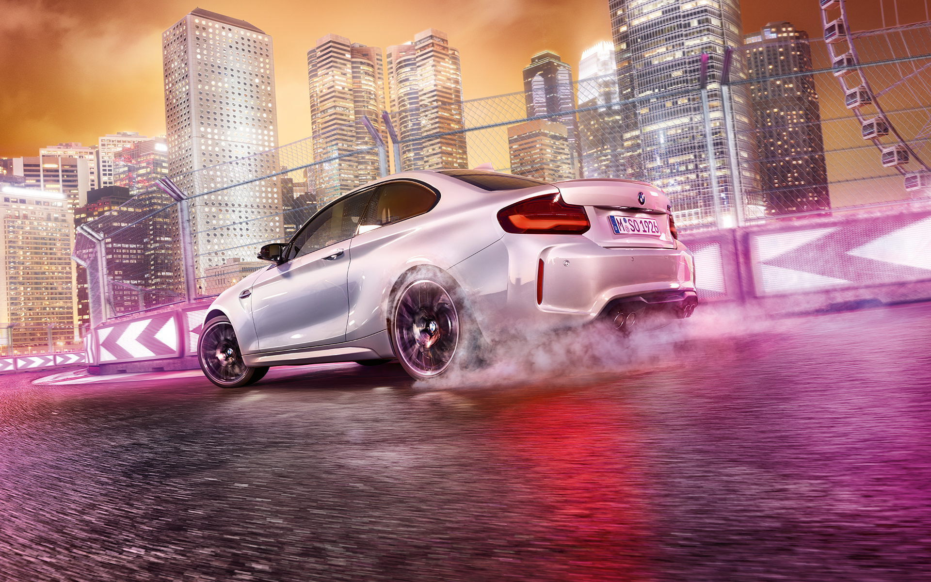 BMW M2 Competition accelerează Automobilul BMW M2 Competition alb condus pe un circuit de curse în faţa unui orizont nocturn.