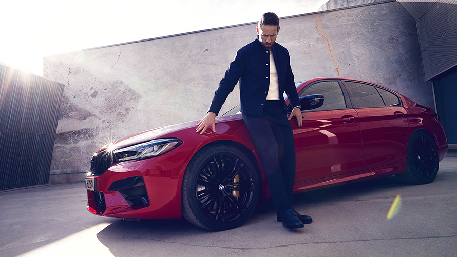 Imagine cu trei sferturi din partea frontală a BMW M5 Competition, în Roşu Imola de la BMW Individual