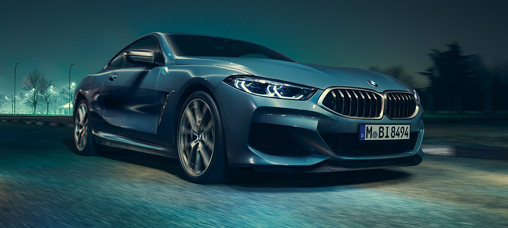 Imagine cu trei sferturi din partea frontală a BMW M850i xDrive Coupé. Imagine cu trei sferturi din partea frontală a BMW M850i xDrive Coupé în Albastru Barcelona metalizat, rulând.