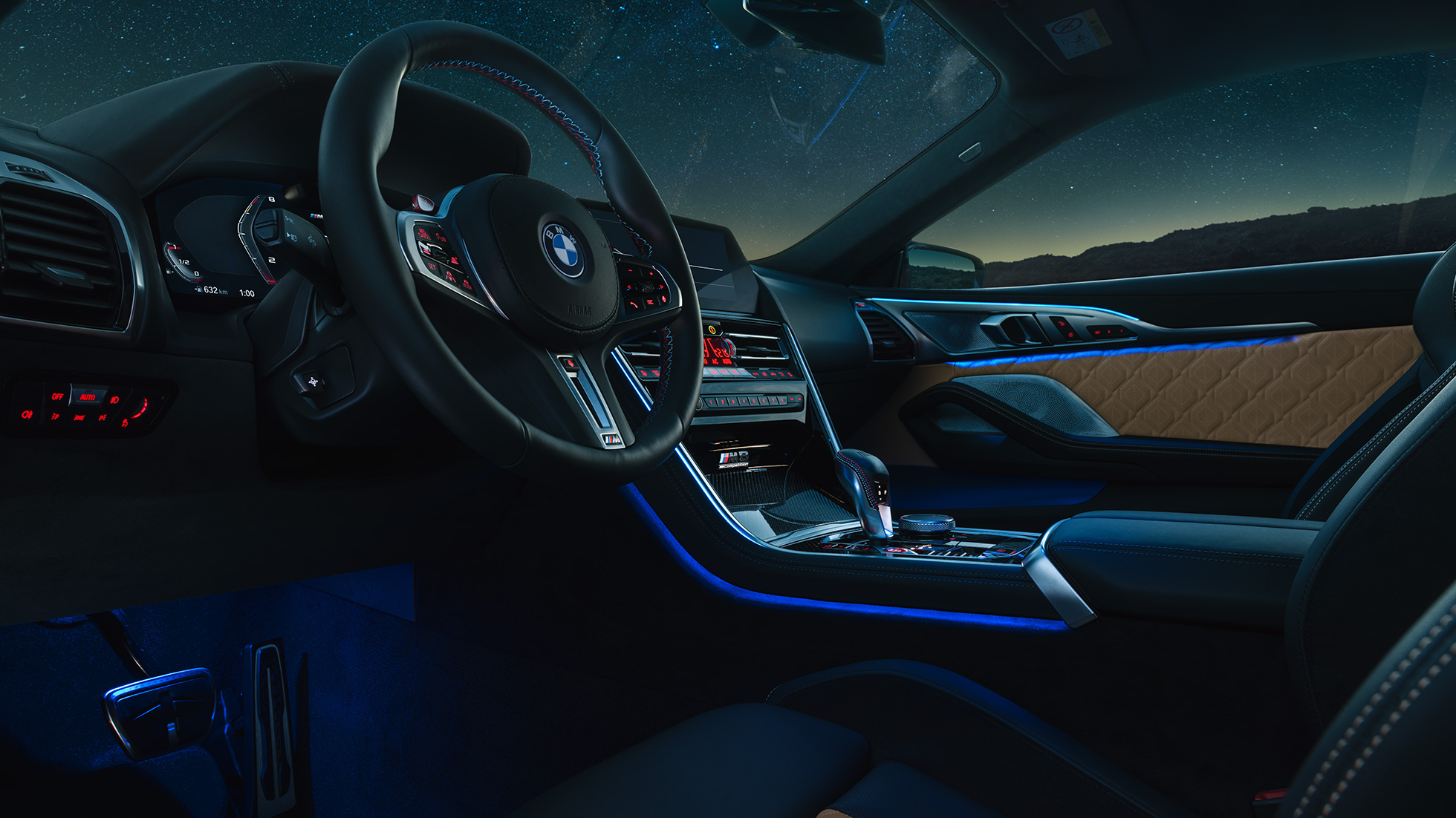 Habitaclu BMW M8 Competition Coupé. Imagine cu habitaclul BMW M8 Competition Coupé, pe timp de noapte, cu volan M îmbrăcat în piele şi lumină ambientală albastră.