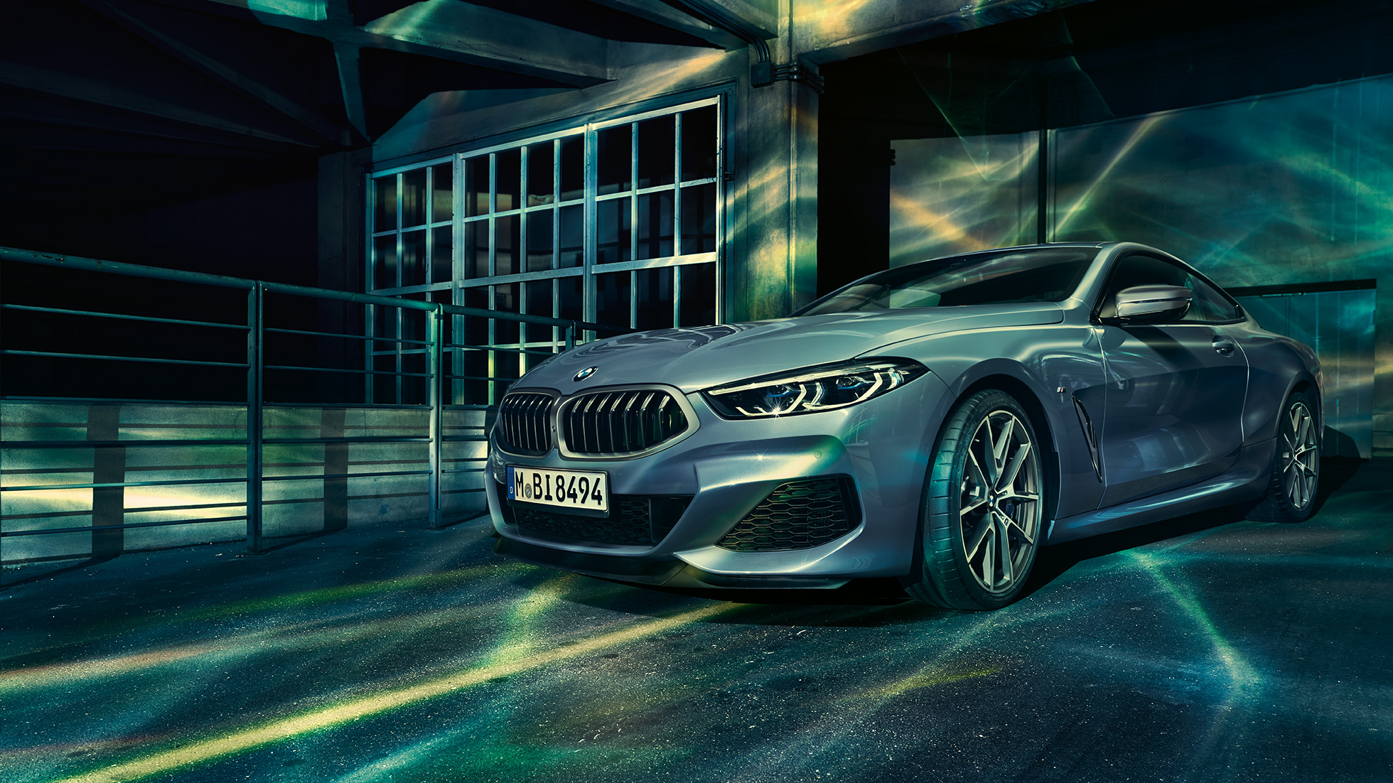 Imagine cu trei sferturi din partea frontală a BMW M850i xDrive Coupé. Imagine cu trei sferturi din partea frontală a BMW M850i xDrive Coupé în Albastru Barcelona metalizat, staţionând în faţa unei clădiri.