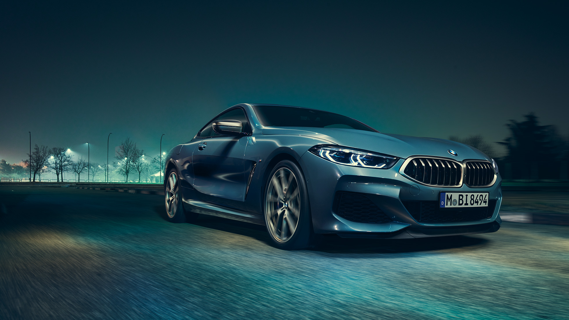 Imagine cu trei sferturi din partea drepată faţă a BMW M850i xDrive Coupé. Imagine cu trei sferturi din partea drepată faţă a BMW M850i xDrive Coupé în Albastru Barcelona metalizat, rulând pe timp de noapte.