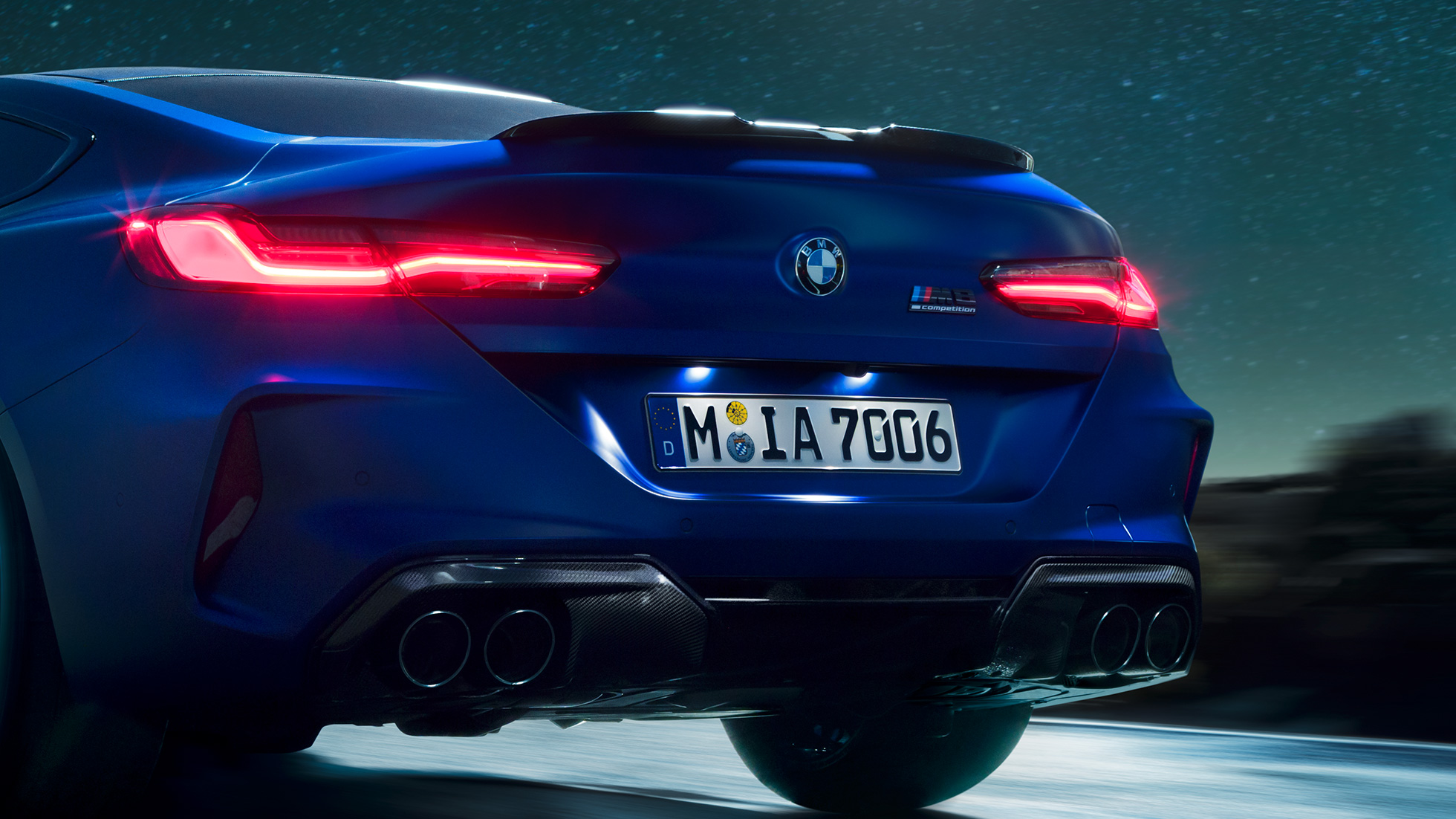 Difuzor M în Negru Carbon. Imagine în prim-plan cu partea spate a BMW M8 Competition Coupé în Albastru Marina Bay metalizat, cu difuzor M în Negru Carbon, pe timp de noapte.