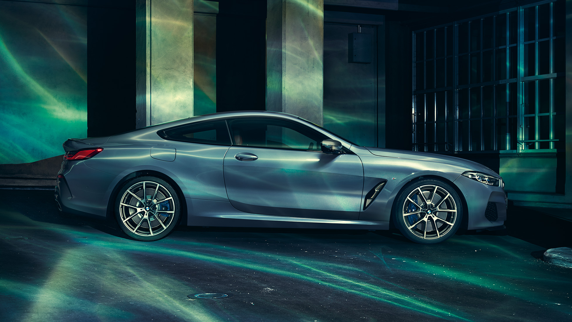 Perspectivă laterală a BMW M850i xDrive Coupé. Perspectivă laterală a BMW M850i xDrive Coupé în Albastru Barcelona metalizat, staţionând în faţa unei clădiri.