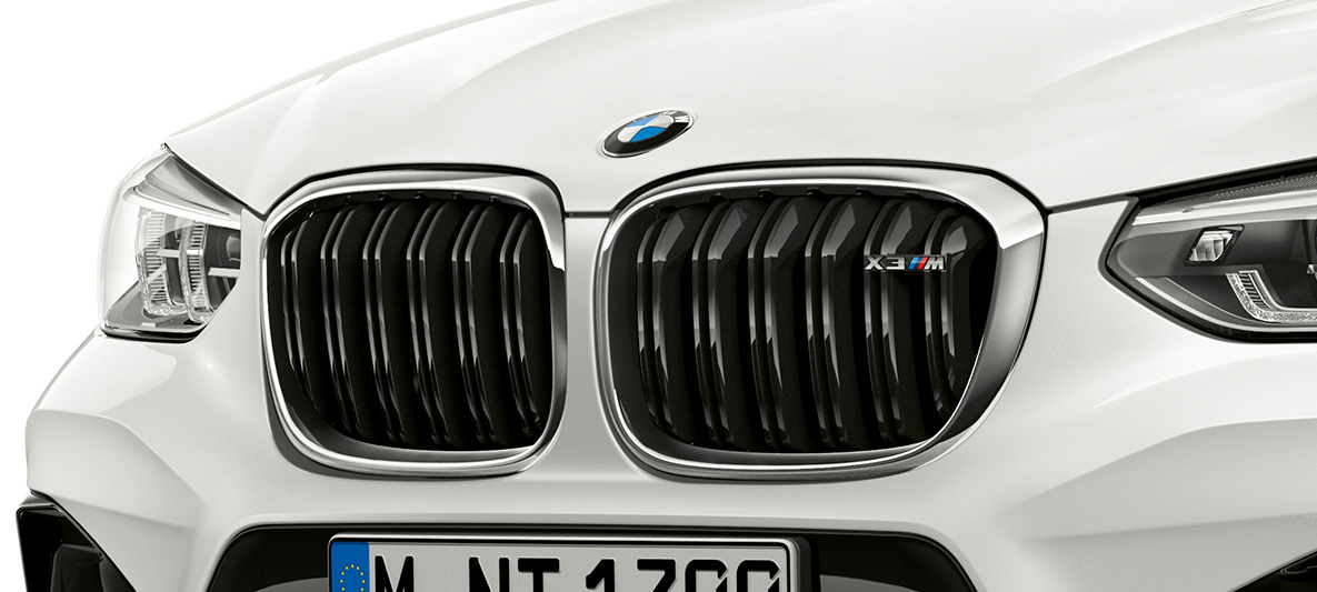 Imagine cu BMW X3 M, cu grilă M a radiatorului. Imagine cu partea frontală exterioară a BMW X3 M în Alb Alpine, cu grilă M a radiatorului cu detalii cromate şi inscripţionarea denumirii modelului.