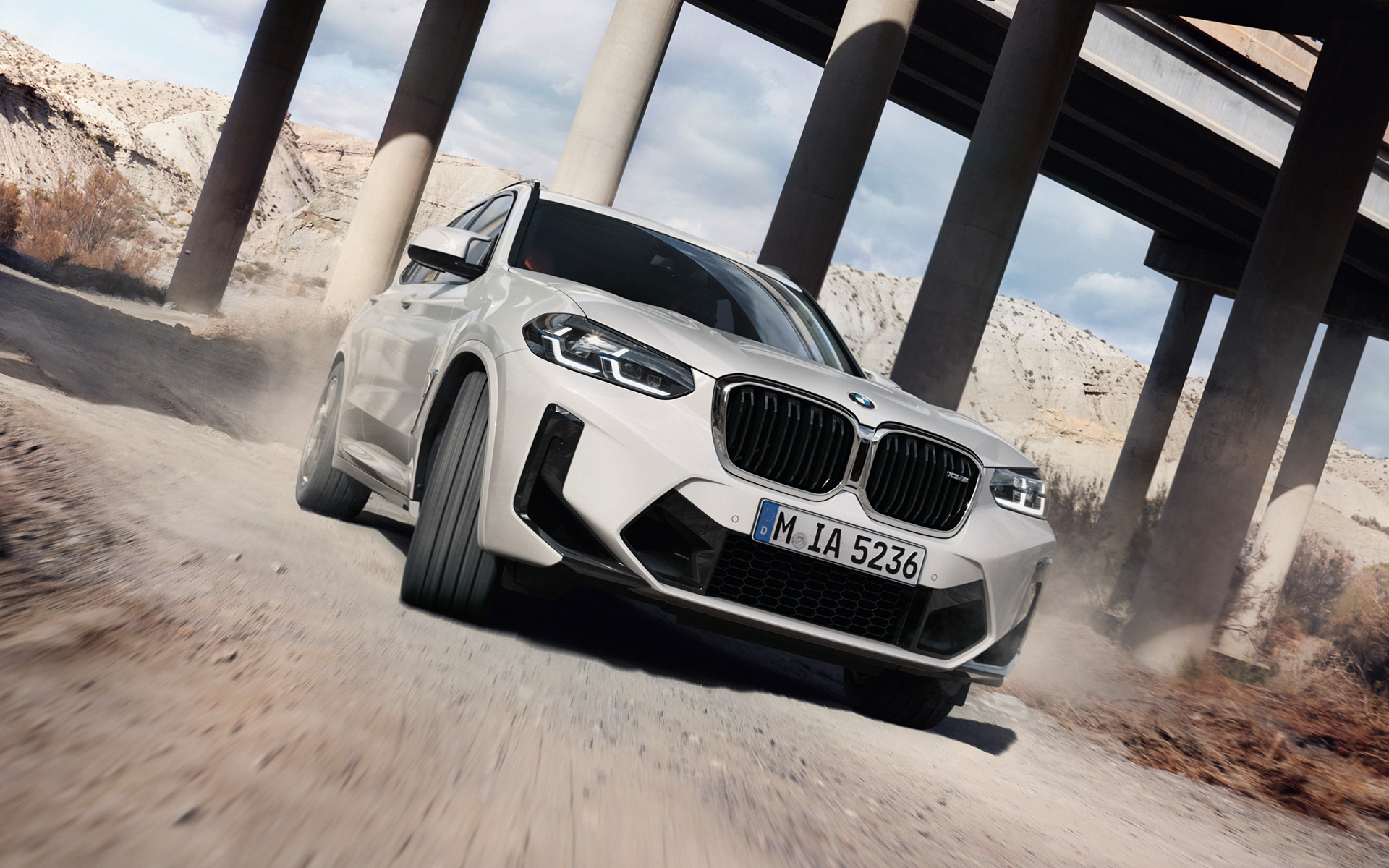 Imagine cu trei sferturi din partea frontală a unui BMW X3 M F97 LCI Facelift 2021 Alb Alpine în timp ce intră într-un viraj