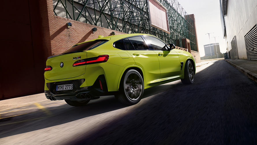 Imagine cu trei sferturi din partea frontală a unui BMW X4 M Competition F98 LCI 2021 Imagine cu trei sferturi din partea frontală a unui BMW X4 M Competition F98 LCI 2021 Galben Sao Paulo care se deplasează într-o zonă industrială