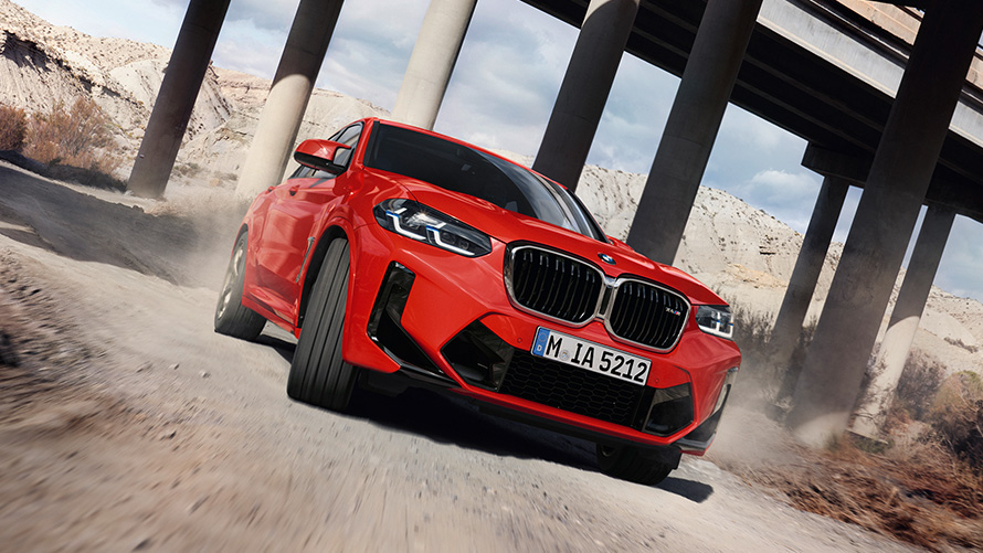 Imagine cu trei sferturi din partea frontală a unui BMW X4 M F98 LCI Facelift 2021 Roşu Toronto în dreptul unui pod