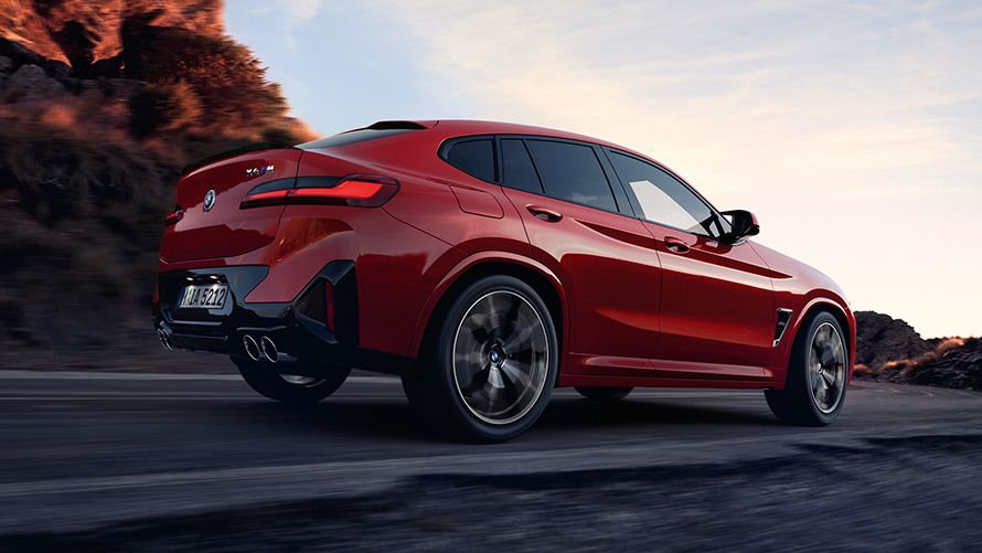 Imagine cu trei sferturi din partea din spate a unui BMW X4 M F98 LCI Facelift 2021 Roşu Toronto în timp ce se deplasează pe o şosea