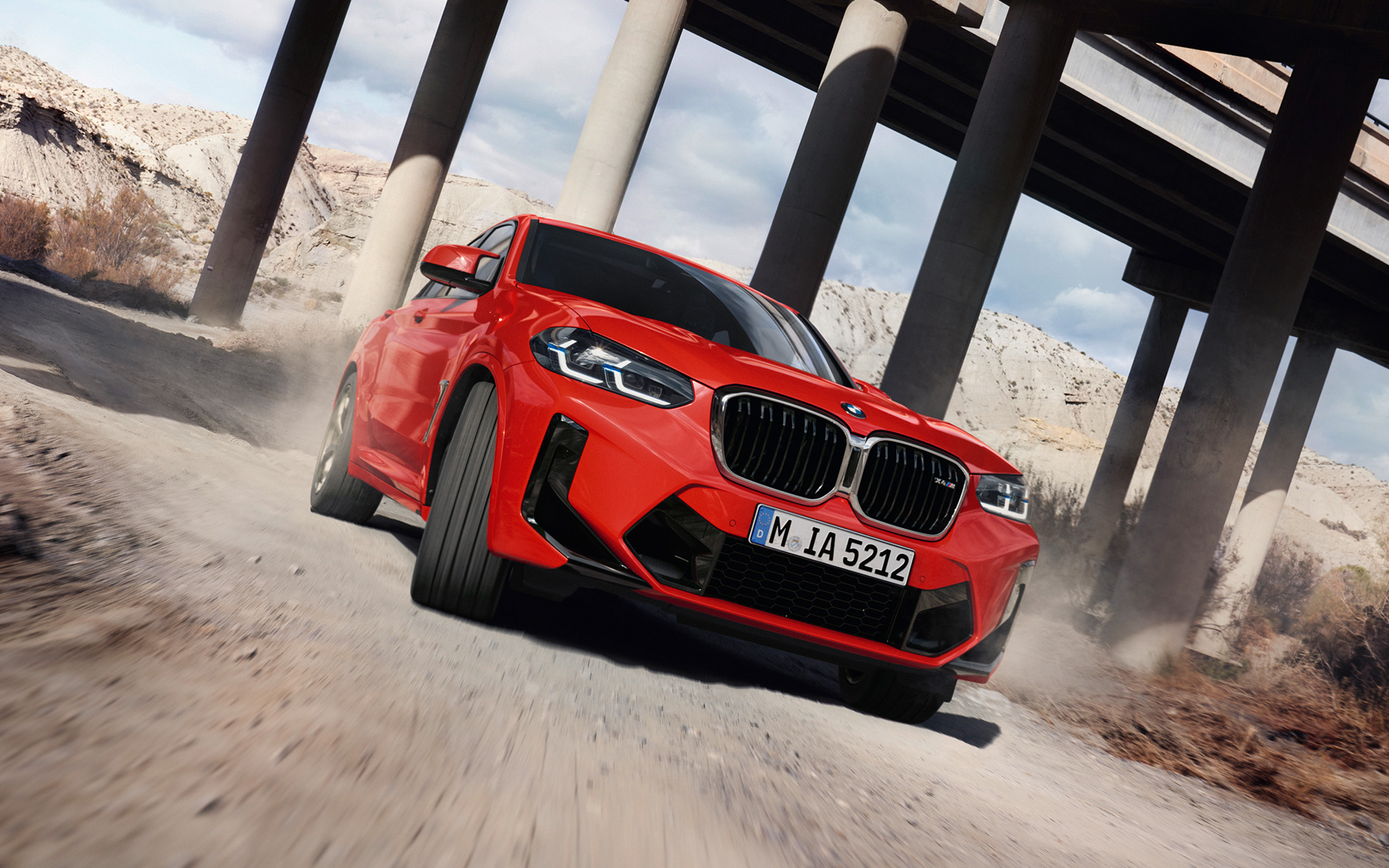 Imagine cu trei sferturi din partea frontală a unui BMW X4 M F98 LCI Facelift 2021 Roşu Toronto în dreptul unui pod
