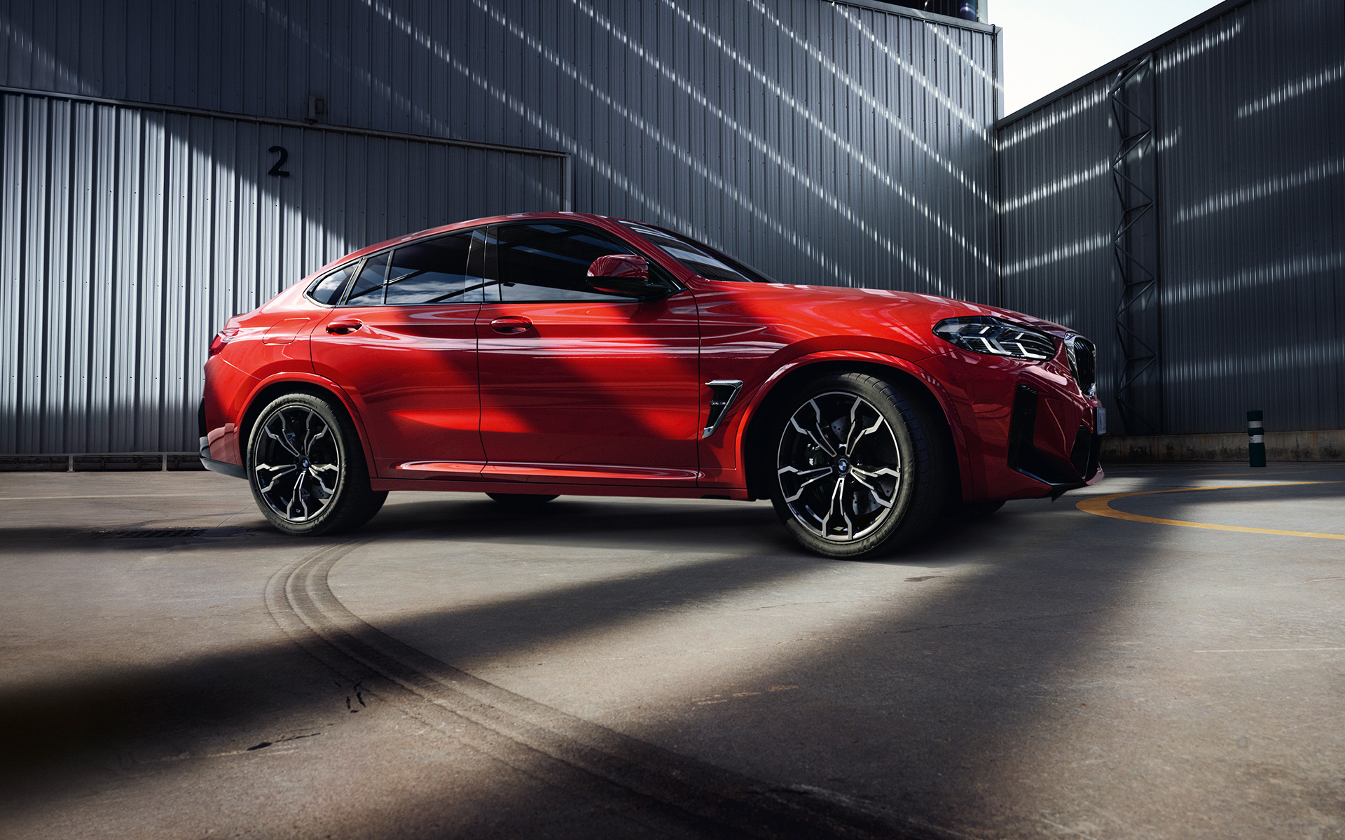 Imagine din partea laterală a unui BMW X4 M F98 LCI Facelift 2021 Roşu Toronto în faţa unei fabrici