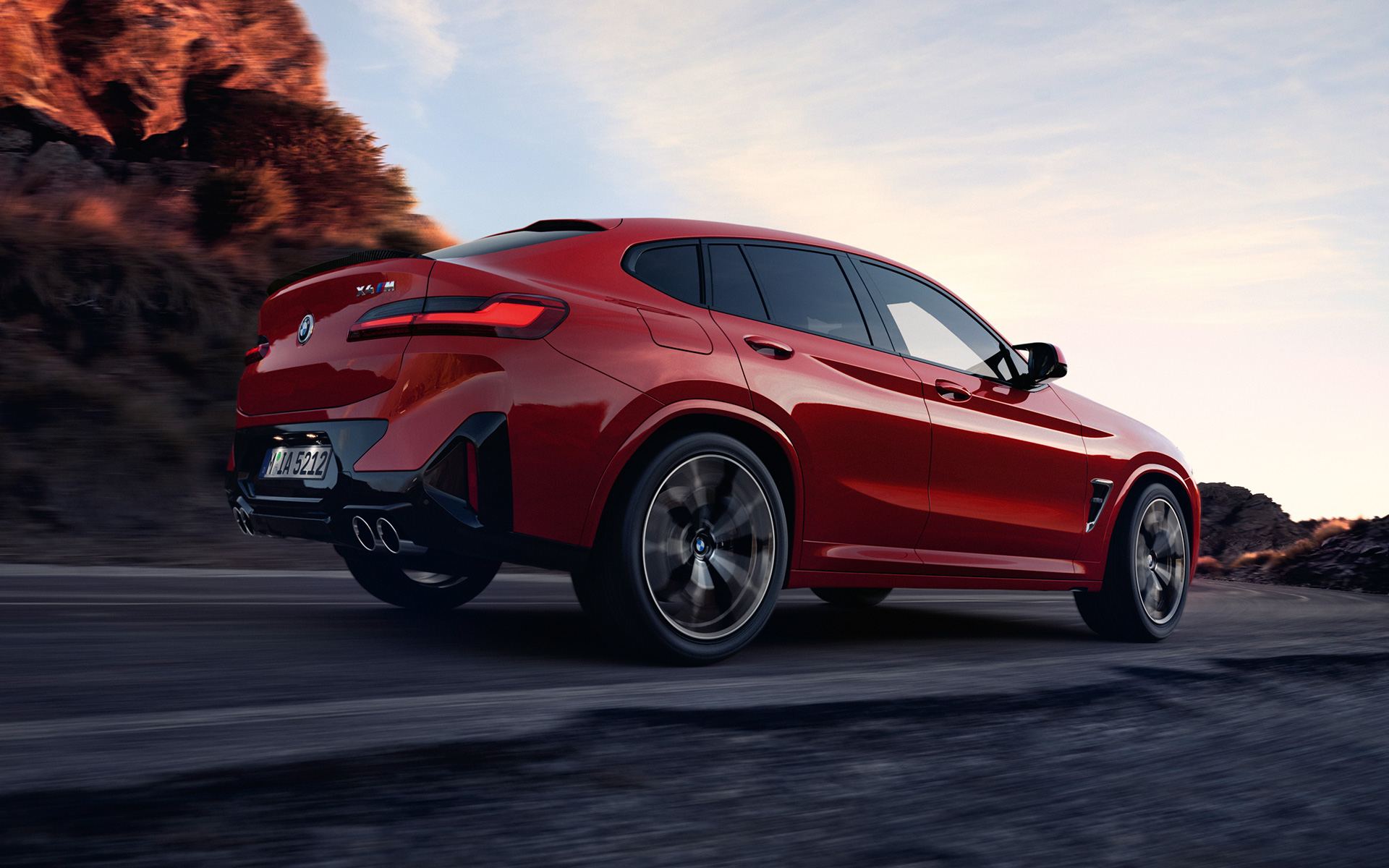 Imagine cu trei sferturi din partea din spate a unui BMW X4 M F98 LCI Facelift 2021 Roşu Toronto în timp ce se deplasează pe o şosea